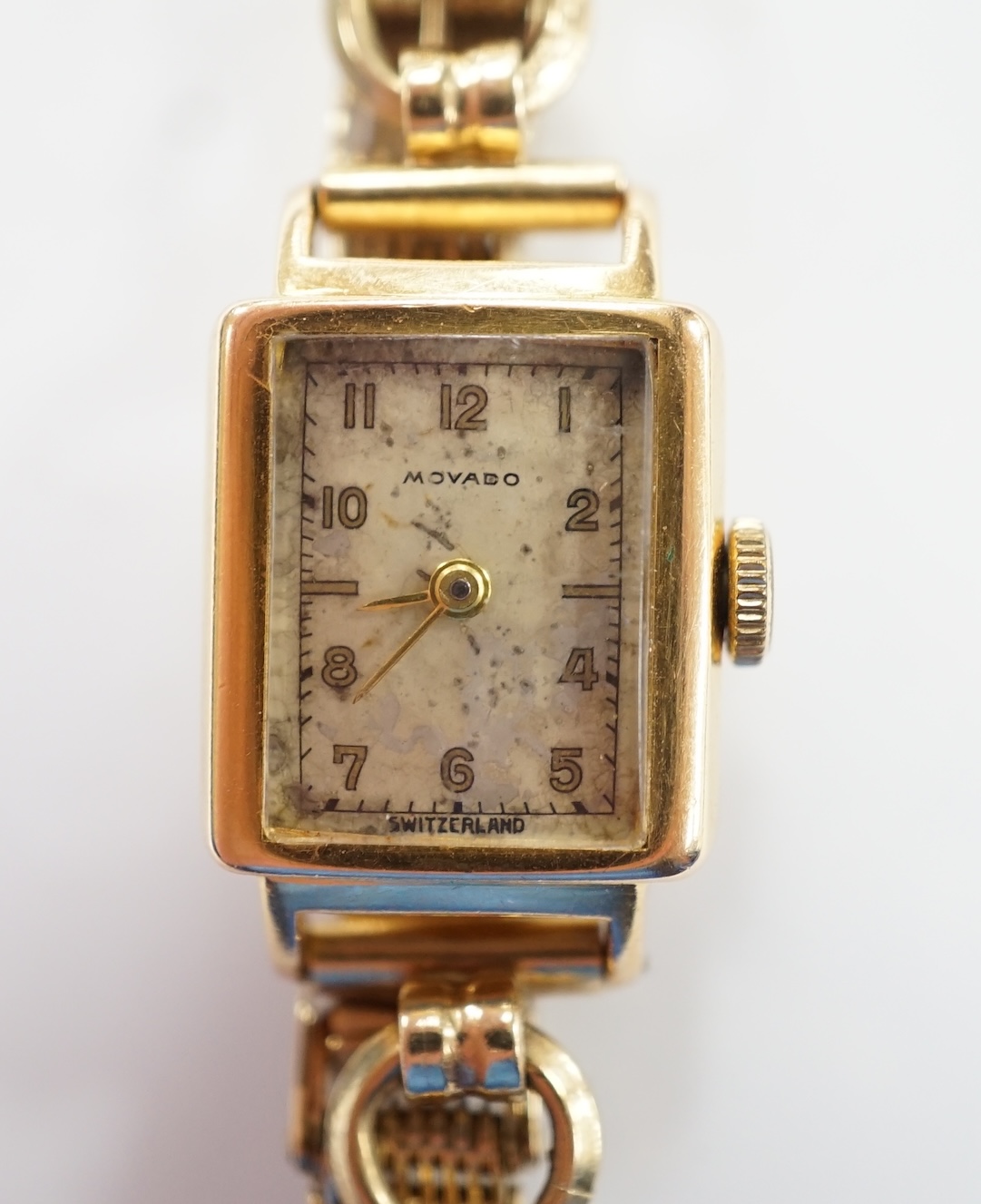 A lady's 18ct gold Movado manual wind wrist watch, on a 9ct gold bracelet. Fair condition